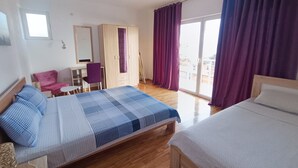 A hotel room with a bed, a desk, a chair, a wardrobe, and a balcony with curtains. - Cozy Apartment With sea View (Bar)