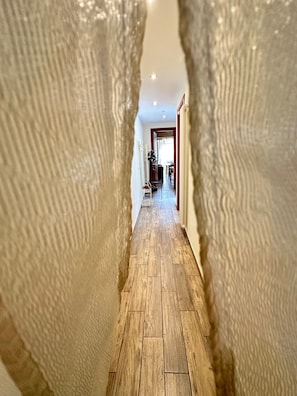 A hallway with wooden flooring, a white chair, and a dining area in the background. - Holiday Home 'Il Piccolo Rifugio' with Private Pool, Garden and Wi-Fi (Figline Valdarno)