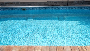 Una piscina con cubierta de madera y paredes de piedra.