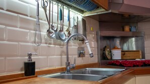 Una cocina con un lavamanos de acero inoxidable, encimera de madera y utensilios colgantes.