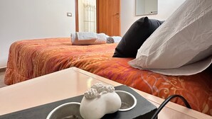 Una habitación de hotel con cama, mesita de noche de madera, espejo y puerta.