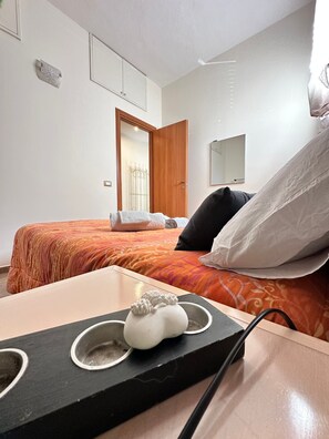 A hotel room with a bed, a wooden nightstand, a mirror, and a door. - Holiday Home 'Il Piccolo Rifugio' with Private Pool, Garden and Wi-Fi (Figline Valdarno)