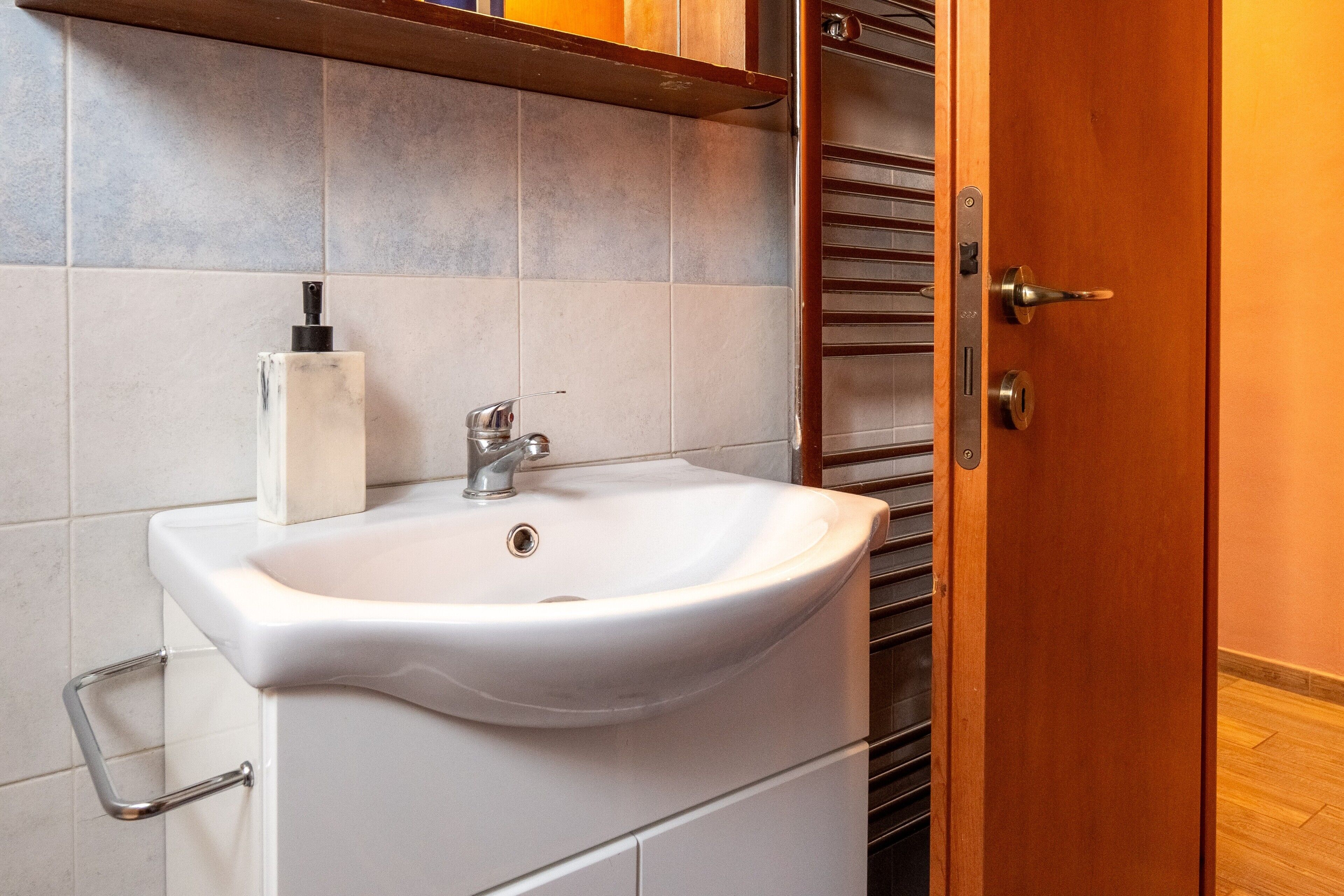 Ein Badezimmer mit einem weißen Waschbecken, einer Seifenspender und einem Handtuchhalter.