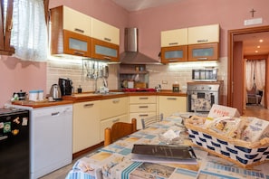 A kitchen with wooden cabinets, a microwave, a stove, and a dining table with a basket of bread.