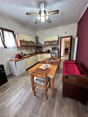 Une cuisine de taille réduite comprenant une table à manger, des chaises, un canapé et un ventilateur de plafond.