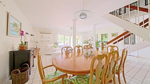 Un'area pranzo con tavolo e sedie in legno, una lampada a sospensione e una scala che conduce a un livello superiore.