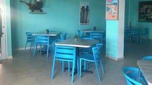 A room with teal walls, blue chairs, and a ship model on the wall. - Buye Apartments (Cabo Rojo)