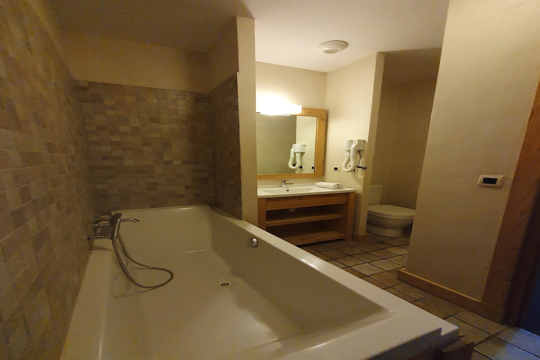 A bathroom with a bathtub, a sink, a toilet, and a mirror.