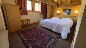 A wooden cabin bedroom with a bed, a bench, a rug, and a painting on the wall. - Getaway for 10 Near Slopes (Les Deux Alpes)