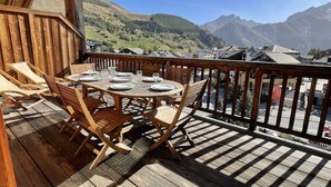 A wooden deck with a table set for dining, overlooking a mountainous landscape. - Getaway for 10 Near Slopes (Les Deux Alpes)
