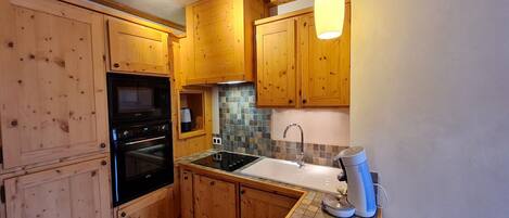 A kitchen with wooden cabinets, a black oven, a microwave, a sink, and a coffee maker.