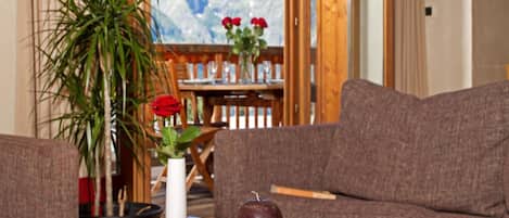 A cozy living room with a chessboard, a book, and a vase with red flowers.