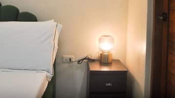Une chambre à coucher avec un lit, une table de chevet avec une lampe et une porte en bois.