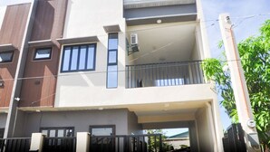 Ein mehrstöckiges Wohngebäude mit flachem Dach, großen Fenstern und einem Balkon im oberen Stockwerk.