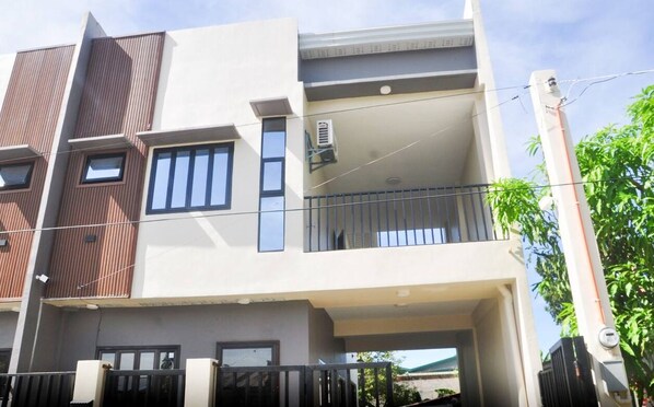 A multi-story residential building with a flat roof, large windows, and a balcony on the upper floor. - Palazzo Olympu Guest House (Bantay)