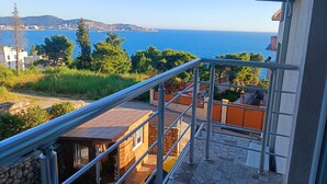 A balcony with a metal railing overlooking a coastal area with buildings and trees. - Comfortable Apartment With sea View (Bar)