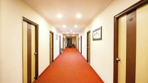 A hotel hallway with a red carpet, wooden doors, and framed pictures on the walls. - Hotel royal inn (Hyderabad)