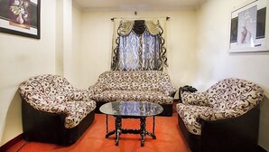A living room with a sofa set, two armchairs, and a coffee table. - Hotel royal inn (Hyderabad)