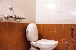 A bathroom with a toilet, a shower, and a wall-mounted faucet. - Hotel royal inn (Hyderabad)