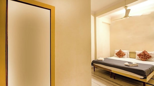 A hotel room with a bed, a bench, and a ceiling fan. - Hotel royal inn (Hyderabad)