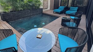 Une terrasse extérieure moderne avec une piscine, des chaises longues et une table.