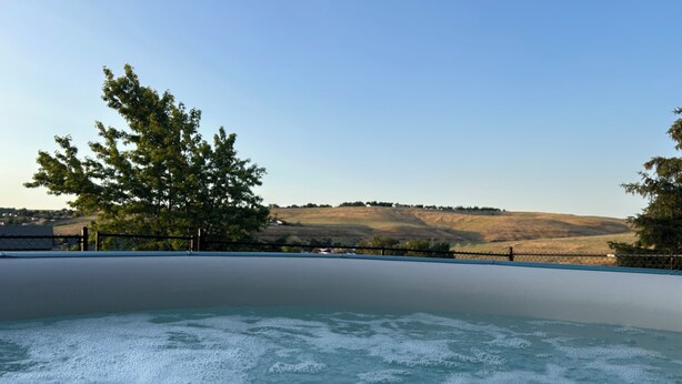 Una piscina con acqua cristallina e vista su un paesaggio collinare.