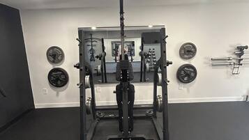 Ein Fitnessraum mit Squat-Stange, Gewichte und einem Spiegel an der Wand.
