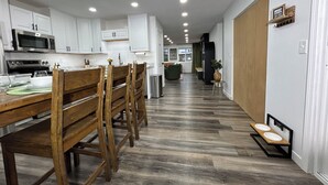 Una cucina moderna con mobili bianchi, un tavolo da pranzo in legno e un forno a microonde integrato.