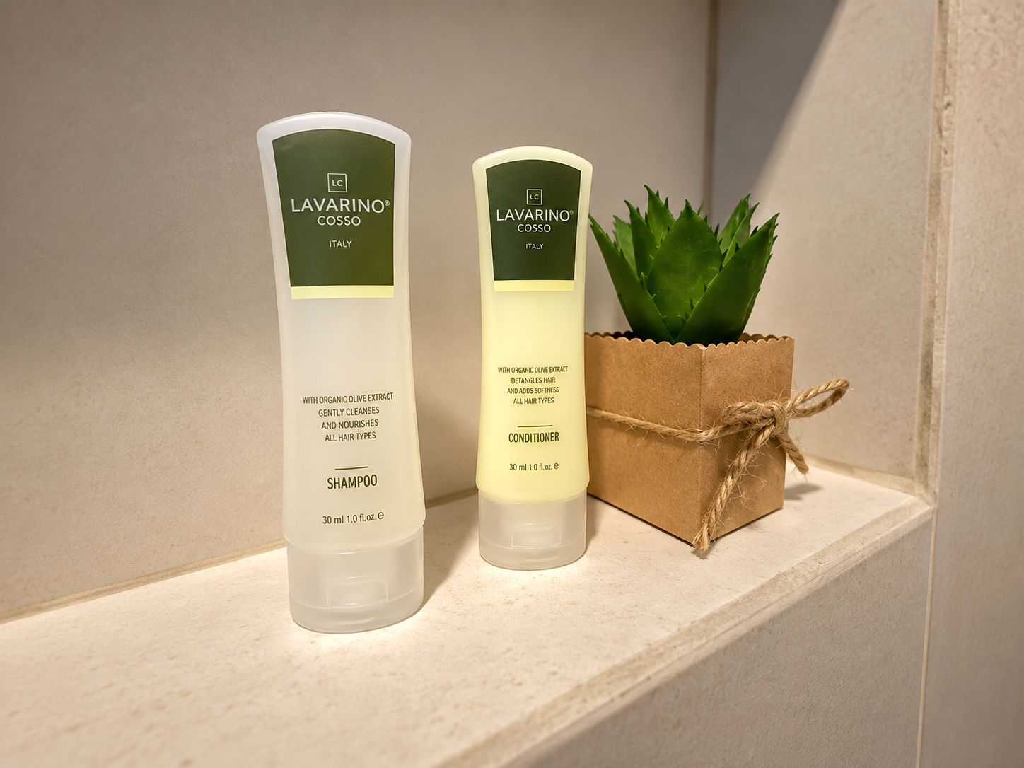 Two bottles of LAVARINO COSSO shampoo and conditioner on a shelf with a small potted plant.