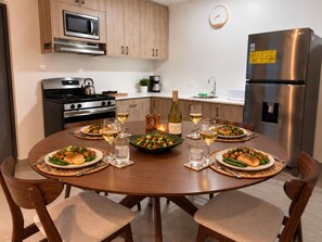 A modern kitchen with stainless steel appliances, wooden cabinets, and a dining table set for a meal.