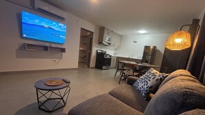 Uma sala moderna com televisão de tela plana, espaço de jantar e cozinha.
