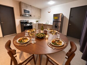 Una cocina moderna con una mesa de comedor preparada para cuatro personas, equipada con microondas, estufa y refrigerador.