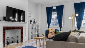 Een woonkamer met een open haard, een televisie, een bank en een salontafel.