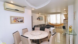 Un comedor con una mesa redonda y sillas, un sofá y un aparador de vidrio.
