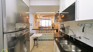 Una cocina moderna con electrodomésticos de acero inoxidable, una encimera negra y salpicadero de azulejos.