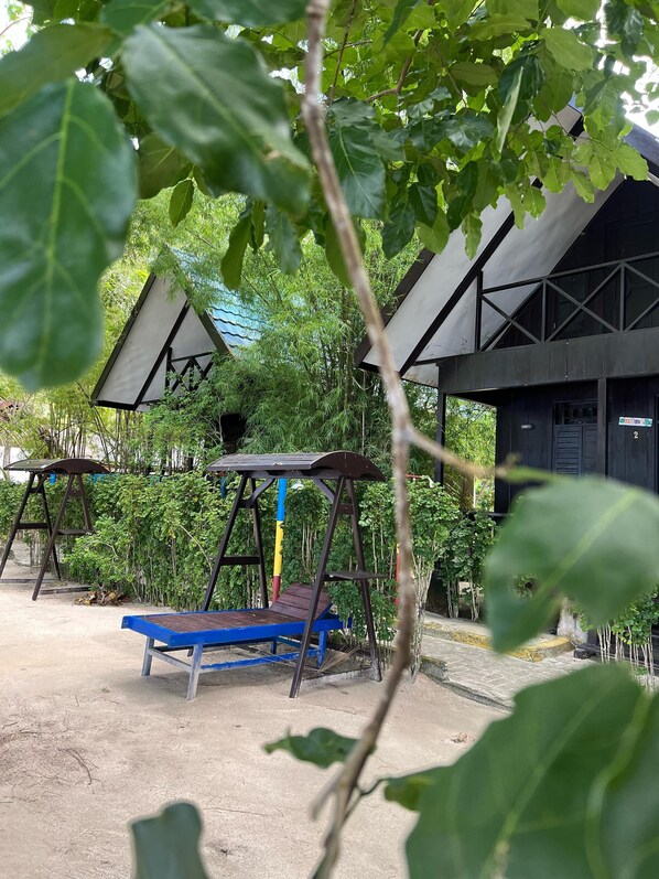 Un espacio exterior rústico con un columpio y un banco azul.