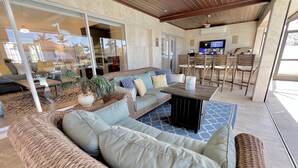 A modern outdoor living area with a curved sofa, a coffee table, and a dining set. - TOP FLORIDA's Villa Pelican Point (Cape Coral)