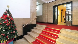 A staircase with red carpet leading to a building entrance, a Christmas tree with ornaments, and a sign above the entrance reading "ED. S. CECILIA". - Domingos (Rio de Janeiro)