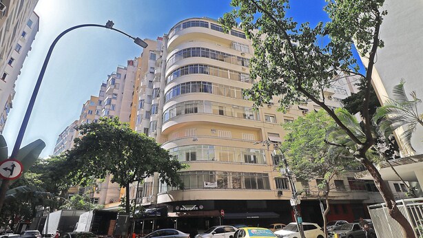 A multi-story building with a curved facade, several balconies, and a visible storefront with signage. - Domingos (Rio de Janeiro)