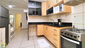 A kitchen with wooden cabinets, a gas stove, a microwave, and a refrigerator. - Domingos (Rio de Janeiro)