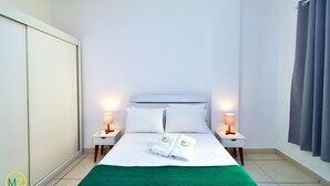 A hotel room with a bed, two bedside tables with lamps, a green throw blanket, and a wardrobe. - Domingos (Rio de Janeiro)