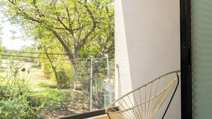 A balcony with a chair and table, a view of trees and a grassy area. - New House in Santa Fe Morelos (Xochitepec)