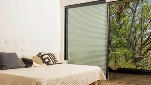 A bedroom with a bed, pillows, a headboard, a window with blinds, and a view of trees. - New House in Santa Fe Morelos (Xochitepec)