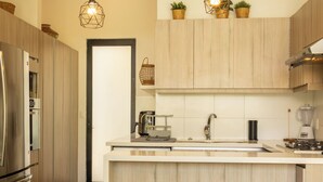 A modern kitchen with wooden cabinets, a stainless steel refrigerator, a built-in oven, a coffee maker, and a blender on the counter. - New House in Santa Fe Morelos (Xochitepec)