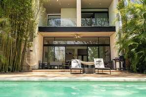 Uma casa moderna com piscina, mobiliário de exterior e uma rede.