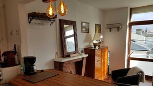 Une cuisine chaleureuse avec un îlot central en bois, une machine à café et une grande fenêtre donnant sur la ville.