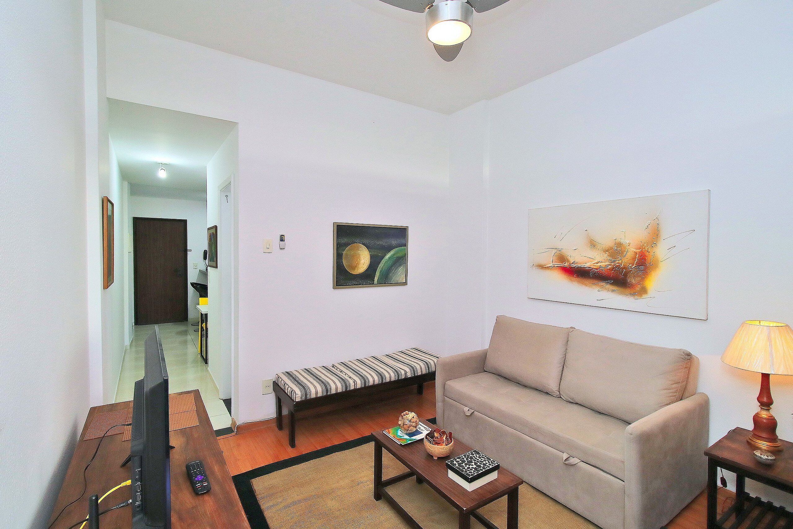 Una sala de estar con sofá, mesa de centro, televisor y lámpara.