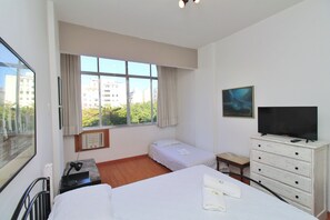 A hotel room with two beds, a TV, a dresser, and a window with a city view. - Nossa Senhora VII (Rio de Janeiro)