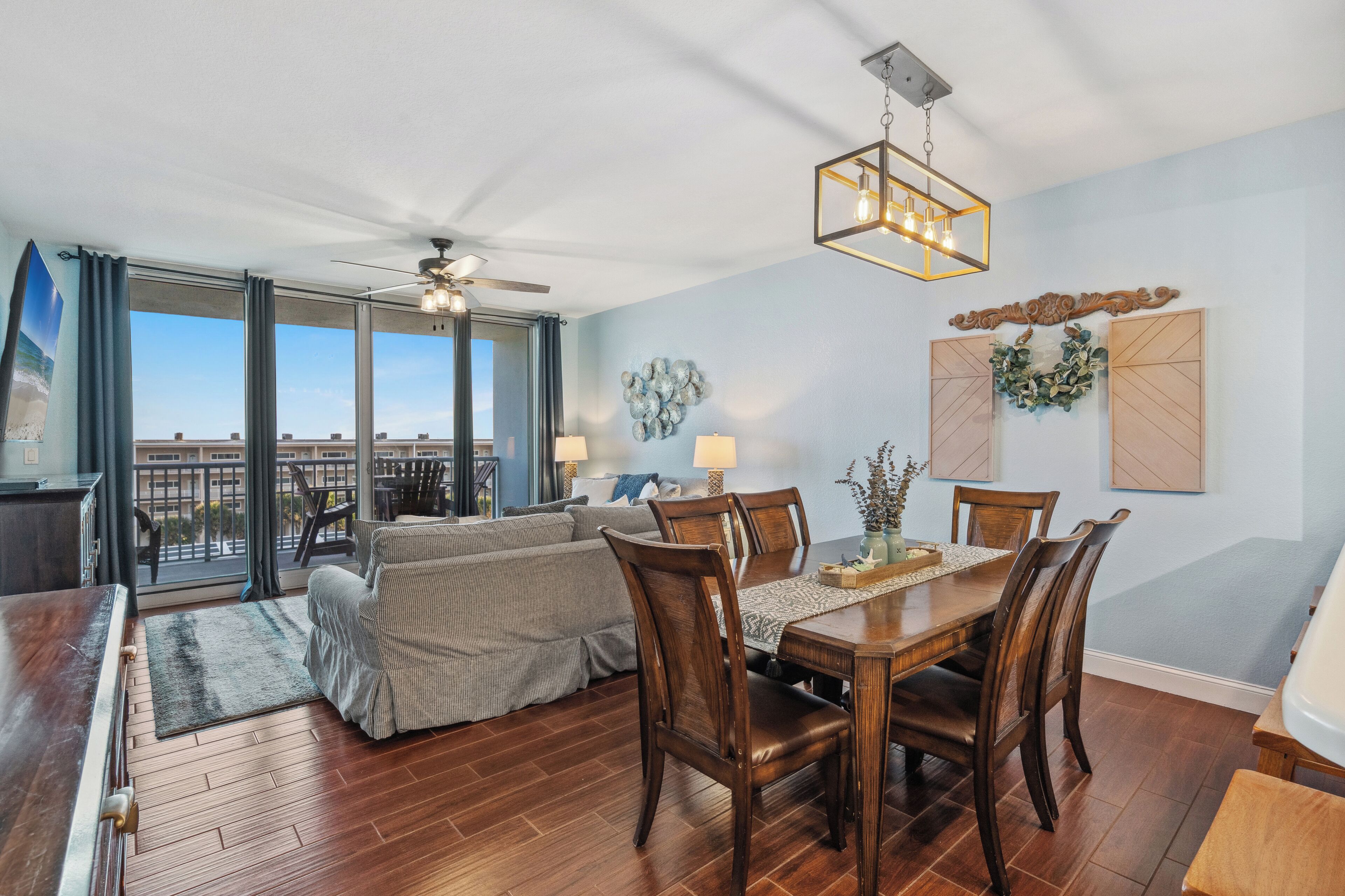 A spacious living area with a dining table, chairs, and a ceiling fan.