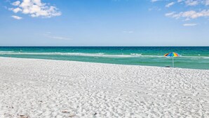 Une plage de sable blanc avec un parasol coloré.